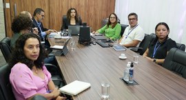 A imagem mostra uma reunião institucional realizada em uma sala de conferências. O grupo está re...