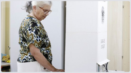 #ParaTodosVerem: Mulher idosa votando em uma urna eletrônica, concentrada, dentro de uma cabine ...