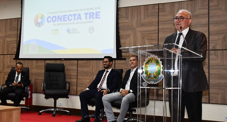 A imagem mostra um evento institucional realizado em auditório. À direita, o presidente do TRE-T...