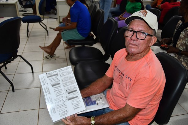 Senhor de 61 anos mostrando sua pasta transparente com todos os comprovantes de votação que possui.