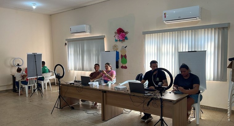 A imagem mostra uma sala iluminada, com paredes claras e janelas cobertas por persianas verticai...