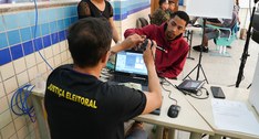 A imagem mostra uma cena de serviço de identificação em um ambiente interno. Um homem de camisa ...