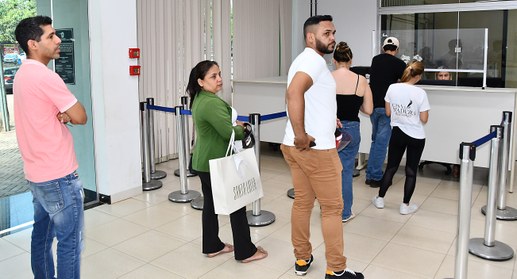 A imagem mostra várias pessoas em uma fila dentro do cartório eleitoral de Palmas. Há divisórias...