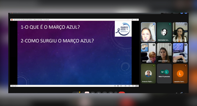 A imagem mostra a tela de uma reunião virtual. No centro, há um slide de apresentação exibido em...