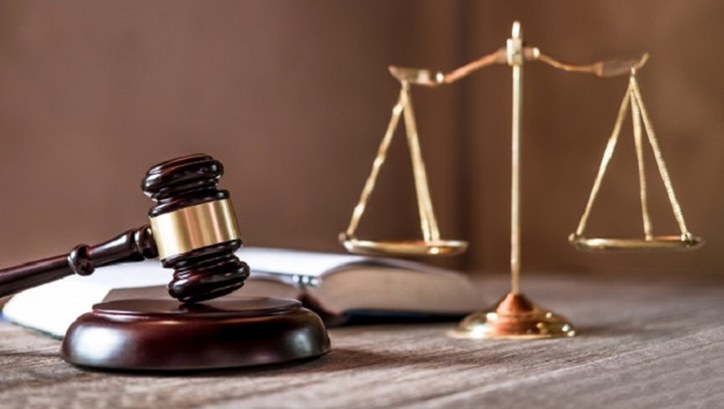 A imagem apresenta elementos simbólicos do sistema de justiça. Em primeiro plano, há um martelo ...