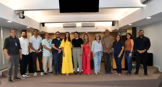 A imagem mostra um grupo de pessoas posando para uma foto oficial em um ambiente institucional. ...