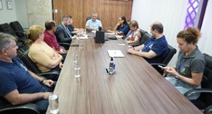 A imagem mostra uma reunião de trabalho a decorrer numa sala de conferências moderna. Cerca de n...