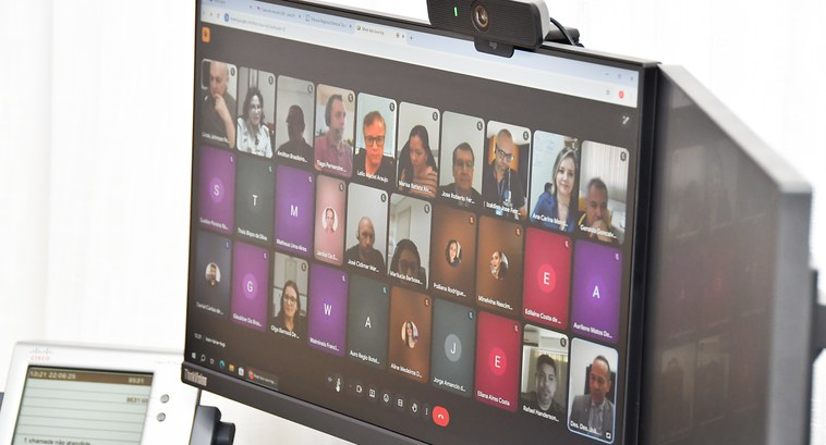 A imagem mostra a tela de um computador durante uma reunião virtual. Diversas pessoas participam...