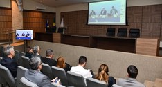 A imagem mostra o auditório do TRE-TO, com pessoas sentadas em cadeiras acolchoadas assistindo a...