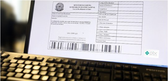 Débitos com a Justiça Eleitoral podem ser pagos via Pix ou cartão de crédito Fotografia de um boleto aberto em um computador com um teclado em frente.