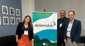A imagem mostra os três servidores do TRE-TO posando ao lado de um banner do evento “6ª edição D...