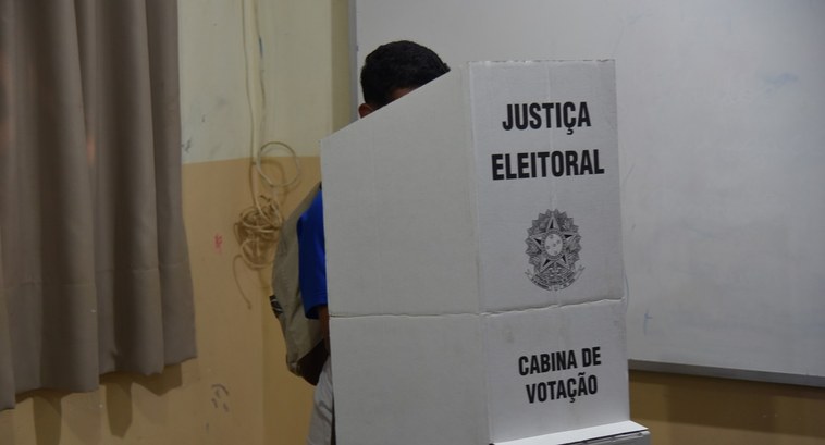 Eleição do Grêmio Estudantil da Escola Frederico José Pedreira Neto, em Palmas, conta com urnas eletrônicas do TRE-TO A imagem mostra um aluno votando em uma cabine de votação da Justiça Eleitoral. A cabine é feita...