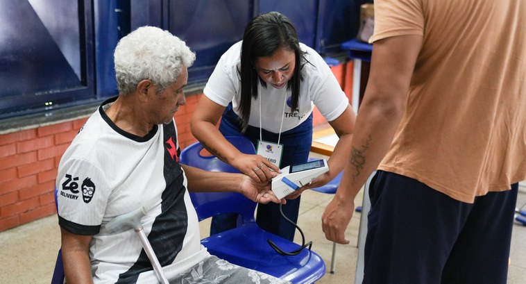 A foto retrata o momento da votação em uma seção eleitoral, onde uma mesária uniformizada com a ...
