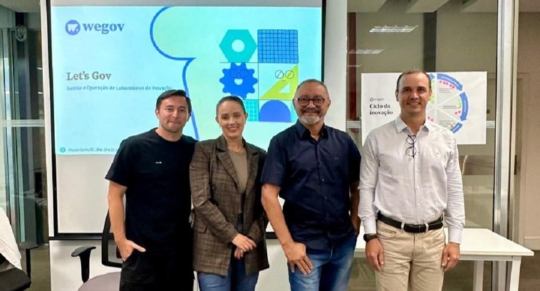 Em busca de inovação, servidores do TRE-TO participam de oficina de capacitação em Florianópolis A imagem mostra quatro pessoas posando para uma foto em um ambiente corporativo, possivelmente a...