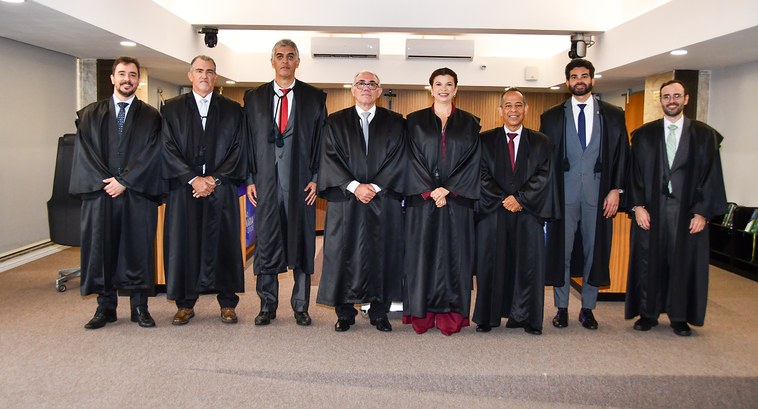 A imagem registra uma sessão solene de posse, no TRE-TO. Nela, oito autoridades estão posicionad...