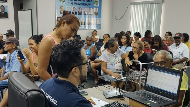 Mais de 200 eleitores são atendidos durante itinerante em Figueirópolis A imagem mostra uma sala cheia de pessoas, em um atendimento coletivo. No primeiro plano, um ser...