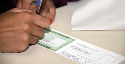Mão assinando título eleitoral Alistamento eleitoral - transferência de domicílio eleitoral - assinatura do título eleitoral