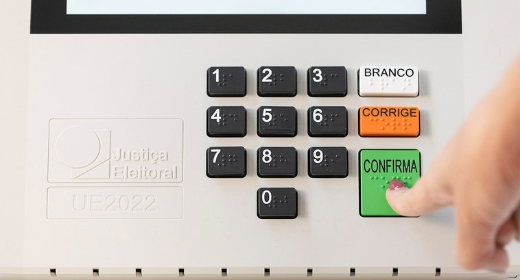 Mulher vota na urna eletrônica 2026 Foto mostra dedo indicador de uma mulher apertando a tecla verde "Confirma" na urna eletrônica