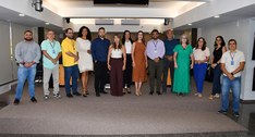A imagem mostra um grupo de pessoas posando para uma foto em um ambiente interno, o salão do Ple...