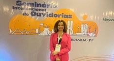 A imagem mostra a juíza Edssandra Barbosa posando em frente ao painel do Seminário Internacional...
