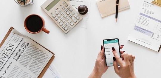 Partido que não prestou contas pode regularizar omissão até o prazo do julgamento Fotografia em fundo branco. Há, do lado direito, a mão de uma mulher segurando um celular. À esq...
