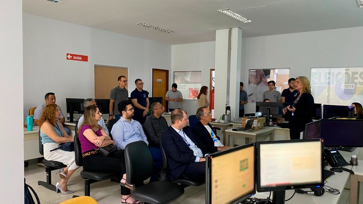 Servidores do TRE-GO visitam o Tocantins para conhecer a Central de Atendimento Virtual ao Eleitor A imagem mostra uma apresentação em um ambiente de escritório. Uma mulher está palestrando para ...
