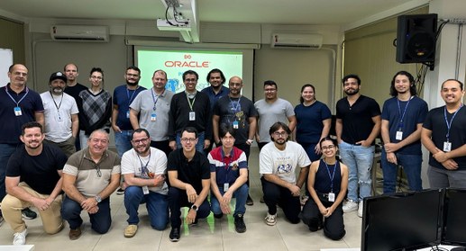 A imagem mostra um grupo numeroso de pessoas reunidas em uma sala de treinamento. Elas estão org...