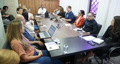 A imagem registra uma reunião de trabalho em uma sala corporativa moderna, onde um grupo de pess...
