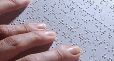 A imagem traz um plano de detalhe focando nas mãos de uma pessoa e em uma folha de papel branco ...
