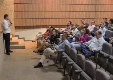 imagem colorida e pessoas assistindo apresentação em auditório