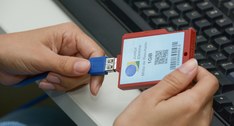 A imagem mostra uma pessoa conectando um dispositivo de armazenamento de mídia de resultado, de ...