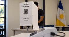 #ParaTodosVerem: fotografia de um local de votação, com uma pessoa atrás de uma cabine de votaçã...